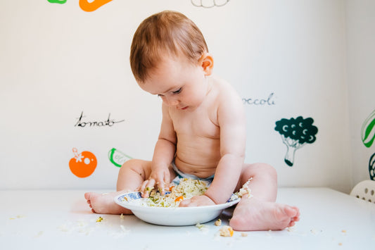 A baby explores textures and flavors, highlighting the need for convenient, mess-free feeding solutions like silicone pouches from Lowcountry Littles.