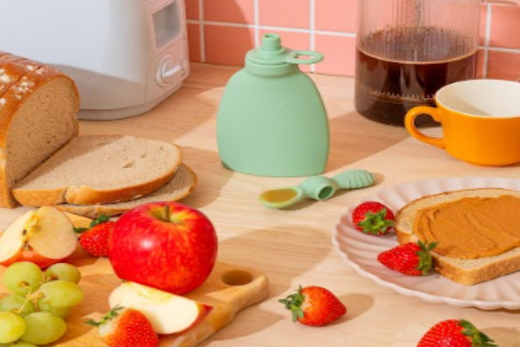 The breakfast setup features fresh apples, grapes, strawberries, bread, peanut butter toast, and a green reusable Palmetto Pouch alongside a coffee press and toaster.