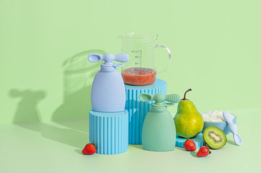 Reusable Palmetto Pouches surrounded by strawberries, kiwi, pear, yogurt, and a beaker of smoothie on a pastel background.