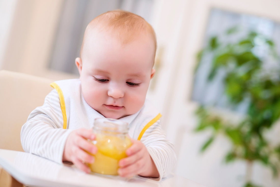 A baby holding a jar of prepackaged baby food, highlighting concerns about lead contamination in commercially available baby foods.